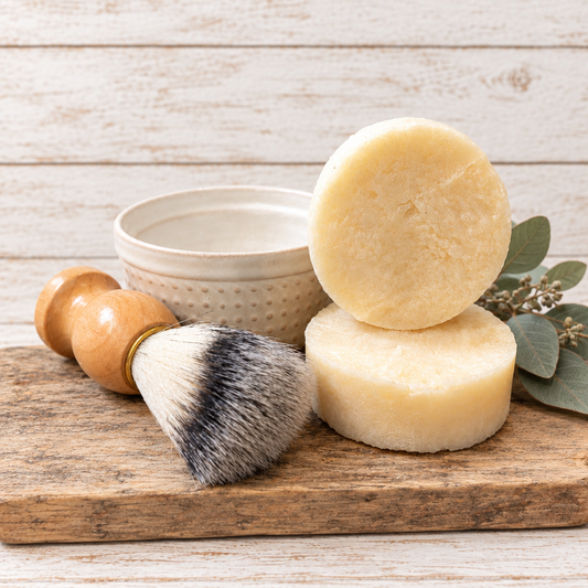 Smooth Love soap, cup, and brush on a weathered wood board with forward-facing greenery